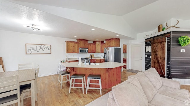 645 Stonebrook Ln, Santaquin, UT 84655 - kitchen with appliances with stainless steel finishes, open floor plan, a breakfast bar, light countertops, and light wood-style flooring