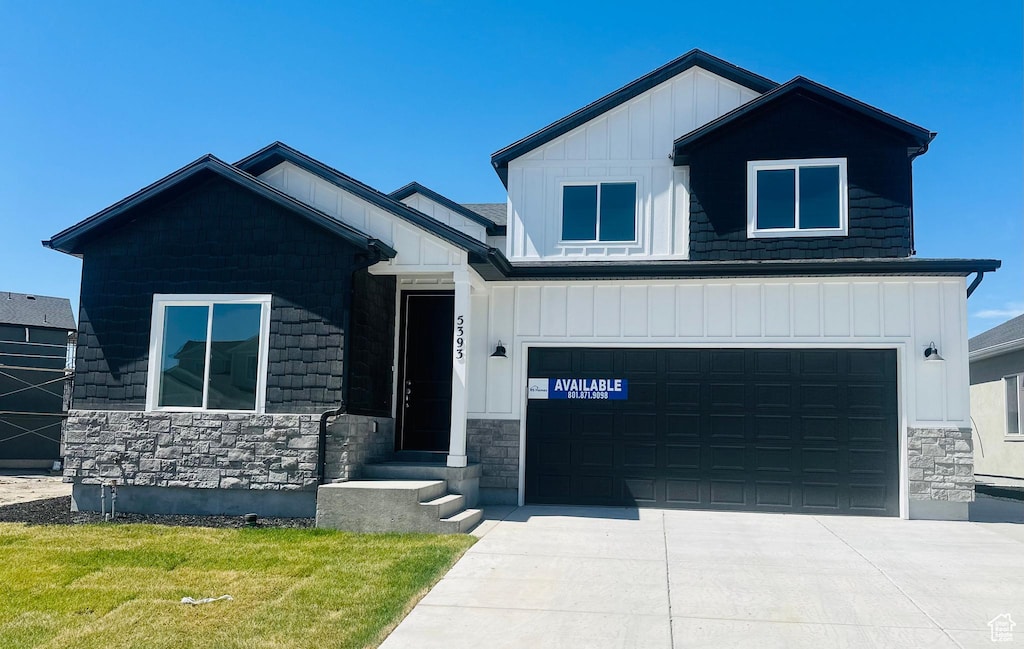 5393 N Orville St Unit 427, Eagle Mountain, UT 84005 - view of front of house with board and batten siding, stone siding, driveway, a garage, and a front lawn