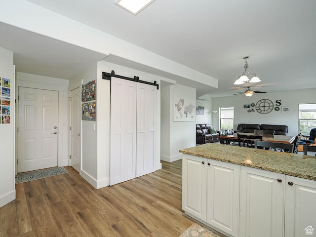 373 N Willow Haven Ave, Lehi, UT 84043 - kitchen with white cabinets, a barn door, light wood-style floors, ceiling fan, and open floor plan