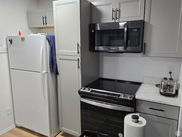 1134 W Illinois Ave S, Salt Lake City, UT 84104 - kitchen featuring freestanding refrigerator, stainless steel microwave, range with electric stovetop, gray cabinetry, and light stone counters