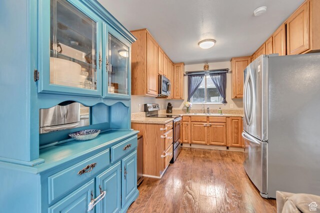 5235 S Glendon St Unit W3, Murray, UT 84123 - kitchen with stainless steel appliances, light countertops, light wood-style floors, glass insert cabinets, and blue cabinetry