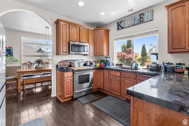 5453 W Mayflower St, West Jordan, UT 84081 - kitchen with stainless steel appliances, recessed lighting, arched walkways, and brown cabinetry