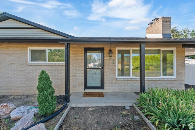 174 W Dawson St, Layton, UT 84041 - view of exterior entry with a chimney, brick siding, and a porch