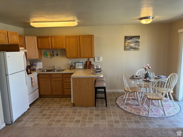 2896 W 3965 S Unit 86, West Haven, UT 84401 - kitchen featuring white appliances, a peninsula, light countertops, a kitchen bar, and brown cabinetry