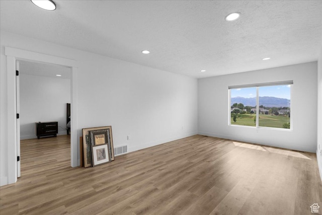 469 N 1360 E Unit 13, Tooele, UT 84074 - unfurnished living room featuring wood finished floors, recessed lighting, a textured ceiling, and a mountain view