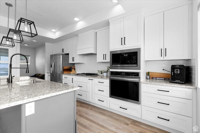 469 N 1360 E Unit 13, Tooele, UT 84074 - kitchen with stainless steel appliances, custom exhaust hood, a tray ceiling, white cabinets, and recessed lighting