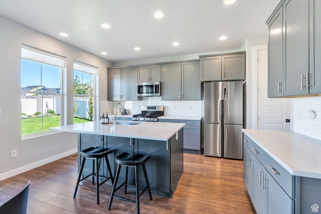 2739 N 3550 W, Lehi, UT 84043 - kitchen featuring stainless steel appliances, gray cabinetry, backsplash, a breakfast bar, and an island with sink