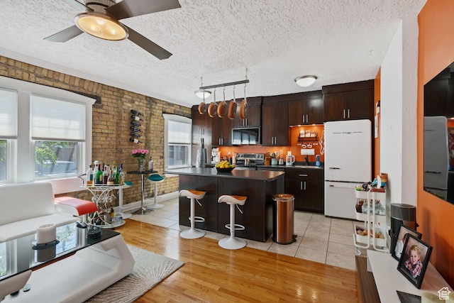 555 E 100 S Unit 206, Salt Lake City, UT 84102 - kitchen featuring appliances with stainless steel finishes, dark countertops, brick wall, a textured ceiling, and a center island