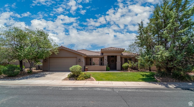 960 N Catalpa Dr, Washington, UT 84780 - mediterranean / spanish home featuring a garage, a tile roof, driveway, stucco siding, and a front lawn