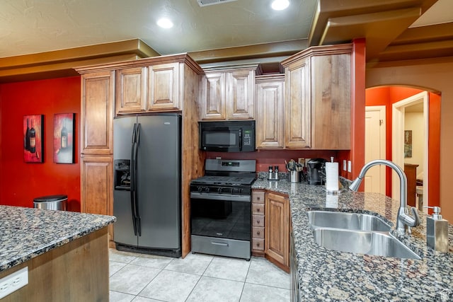 960 N Catalpa Dr, Washington, UT 84780 - kitchen with fridge with ice dispenser, black microwave, stainless steel gas range oven, light tile patterned flooring, and dark stone counters