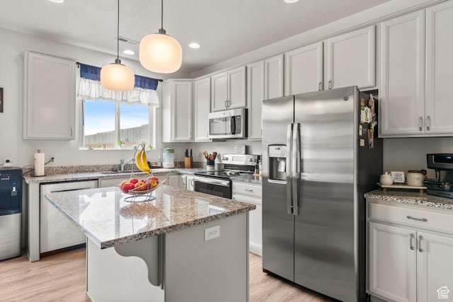 1546 W Parkview Dr, Syracuse, UT 84075 - kitchen with stainless steel appliances, recessed lighting, light stone countertops, a kitchen island, and light wood finished floors