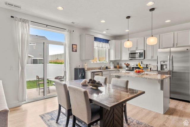 1546 W Parkview Dr, Syracuse, UT 84075 - kitchen with appliances with stainless steel finishes, a kitchen island, light wood-style flooring, light stone counters, and recessed lighting