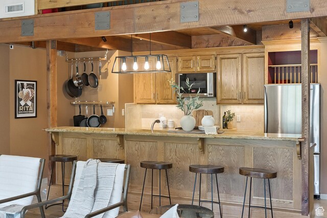 1582 Deer Valley Dr N, Park City, UT 84060 - kitchen featuring appliances with stainless steel finishes, tasteful backsplash, a breakfast bar area, light stone counters, and pendant lighting