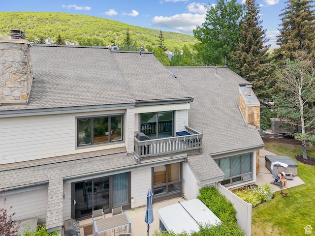 1582 Deer Valley Dr N, Park City, UT 84060 - rear view of property with a balcony, a shingled roof, a view of trees, a chimney, and a patio