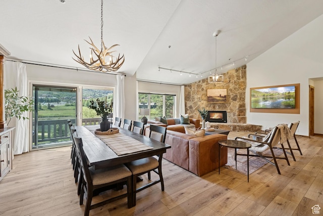1582 Deer Valley Dr N, Park City, UT 84060 - dining area featuring light wood-style floors, a chandelier, rail lighting, a stone fireplace, and high vaulted ceiling
