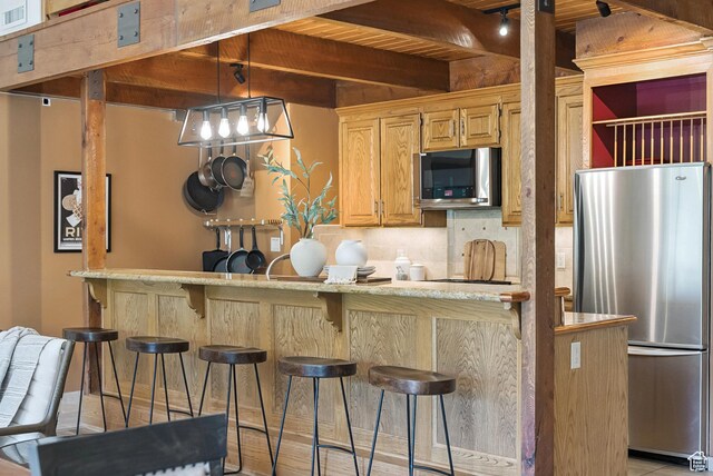 1582 Deer Valley Dr N, Park City, UT 84060 - kitchen featuring stainless steel appliances, beamed ceiling, a kitchen bar, decorative backsplash, and hanging light fixtures