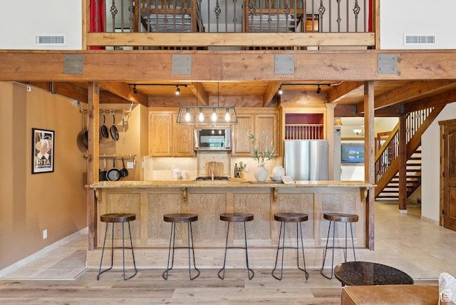 1582 Deer Valley Dr N, Park City, UT 84060 - kitchen featuring appliances with stainless steel finishes, a breakfast bar, beamed ceiling, rail lighting, and decorative backsplash