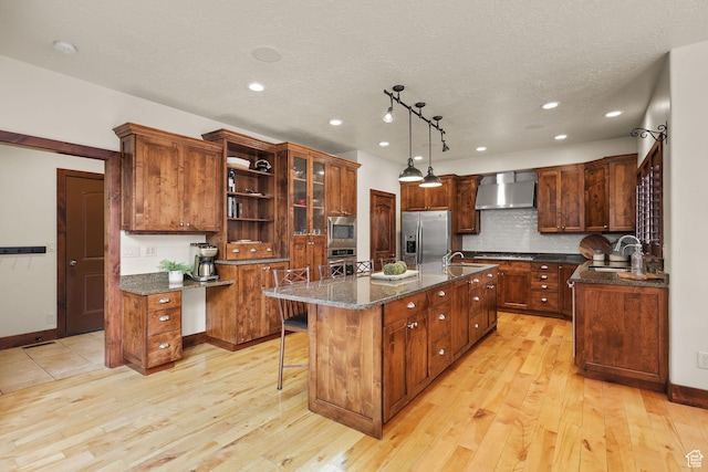 4048 W Ivy Ave, Mountain Green, UT 84050 - kitchen with wall chimney exhaust hood, stainless steel appliances, a kitchen island with sink, light wood-type flooring, and recessed lighting