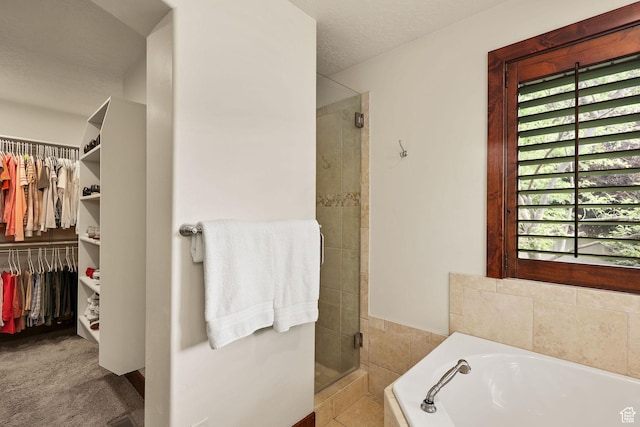 4048 W Ivy Ave, Mountain Green, UT 84050 - full bathroom featuring a stall shower, a garden tub, a walk in closet, and a textured ceiling