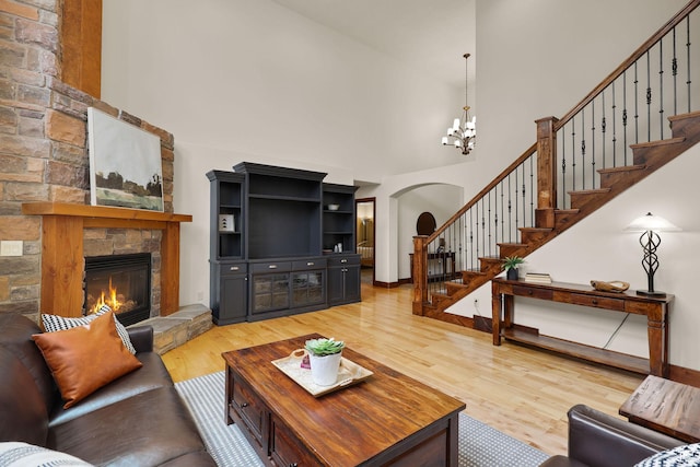4048 W Ivy Ave, Mountain Green, UT 84050 - living room with a towering ceiling, light wood-style flooring, a stone fireplace, arched walkways, and stairs