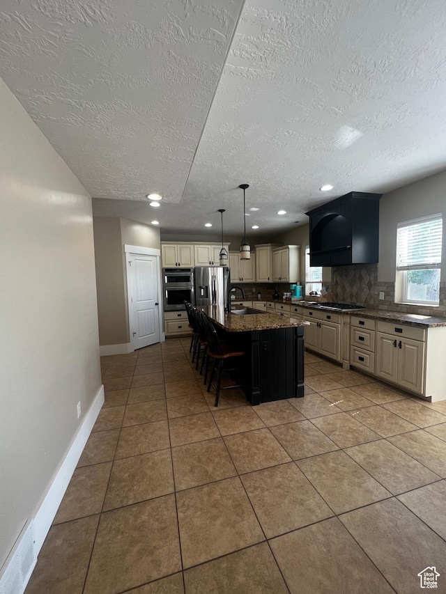 1694 S 710 E, Lehi, UT 84043 - kitchen featuring appliances with stainless steel finishes, cream cabinetry, tasteful backsplash, a kitchen bar, and a textured ceiling