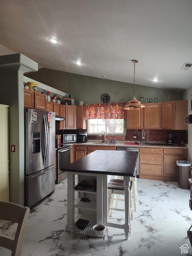 2054 E 140 S, St George, UT 84790 - kitchen with appliances with stainless steel finishes, lofted ceiling, light marble finish floors, decorative backsplash, and brown cabinets