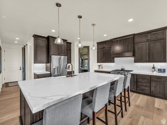 943 Hart Loop, Francis, UT 84036 - kitchen featuring premium appliances, custom exhaust hood, decorative backsplash, light wood-style flooring, and recessed lighting