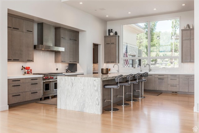1433 Snow Berry St, Park City, UT 84098 - kitchen with wall chimney range hood, range with two ovens, modern cabinets, tasteful backsplash, and a kitchen breakfast bar