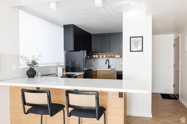 673 E 6th Ave, Salt Lake City, UT 84103 - kitchen with freestanding refrigerator, light countertops, a peninsula, tasteful backsplash, and a kitchen breakfast bar
