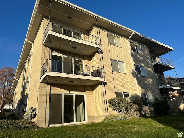 673 E 6th Ave, Salt Lake City, UT 84103 - back of property with a balcony, brick siding, and a yard