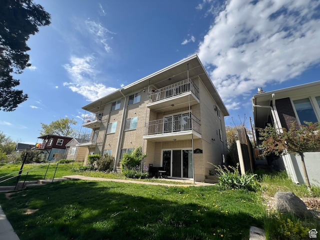673 E 6th Ave, Salt Lake City, UT 84103 - back of house featuring brick siding, a yard, and a balcony