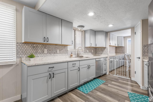 396 S 100 E, Tooele, UT 84074 - kitchen with stainless steel dishwasher, light wood-style floors, tasteful backsplash, a textured ceiling, and light stone countertops