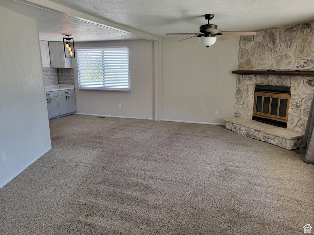 396 S 100 E, Tooele, UT 84074 - unfurnished living room with a ceiling fan, a stone fireplace, carpet, and a textured ceiling
