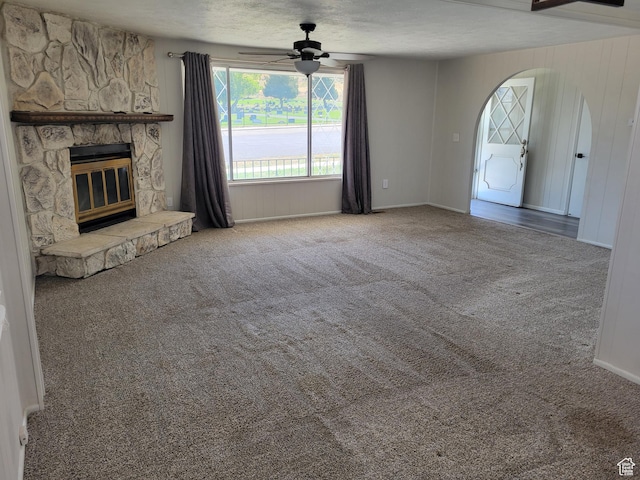 396 S 100 E, Tooele, UT 84074 - unfurnished living room with carpet floors, ceiling fan, a stone fireplace, and arched walkways