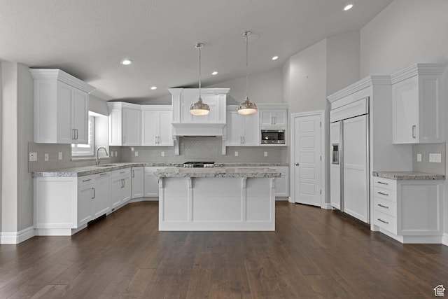 5575 S 1350 E, South Ogden, UT 84403 - kitchen featuring built in appliances, decorative backsplash, white cabinetry, a center island, and dark wood-style flooring