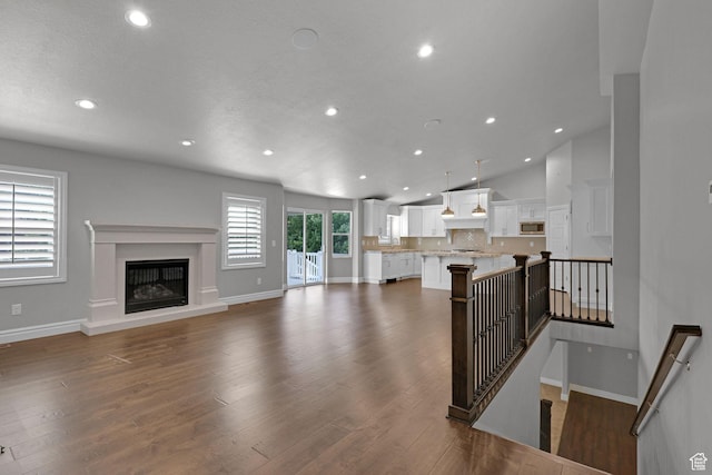 5575 S 1350 E, South Ogden, UT 84403 - unfurnished living room with recessed lighting, dark wood-style floors, a glass covered fireplace, and vaulted ceiling