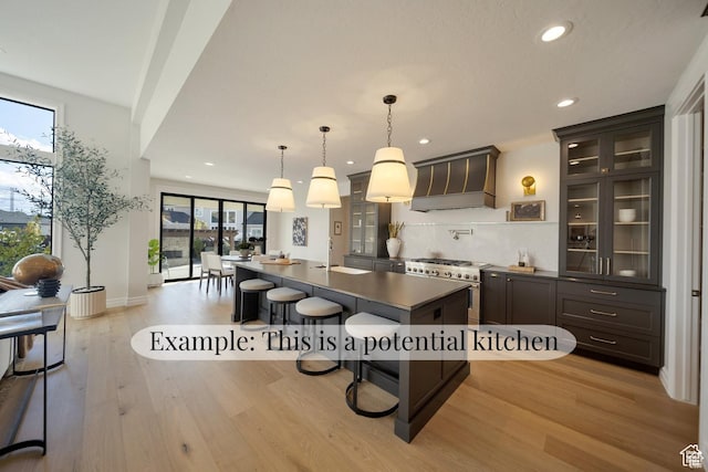 540 S 1375 W, Farmington, UT 84025 - kitchen featuring custom exhaust hood, dark countertops, light wood-type flooring, a kitchen breakfast bar, and a kitchen island with sink