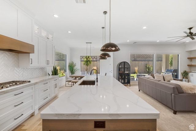 2950 E Naboo Ln, St George, UT 84790 - kitchen with stainless steel gas cooktop, a center island with sink, open floor plan, a ceiling fan, and tasteful backsplash