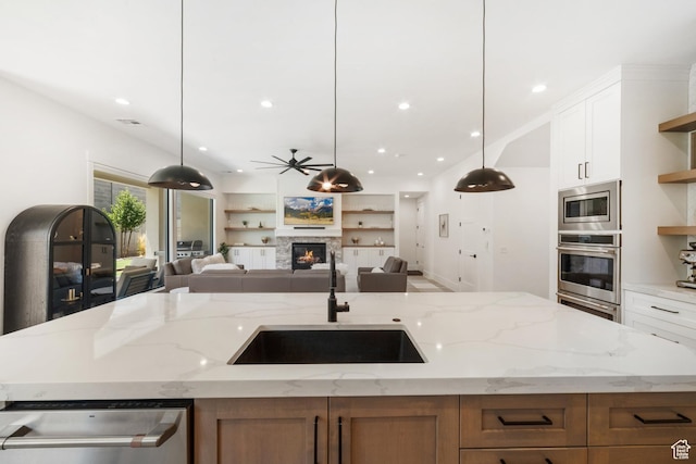 2950 E Naboo Ln, St George, UT 84790 - kitchen with stainless steel appliances, an island with sink, open floor plan, open shelves, and light stone counters