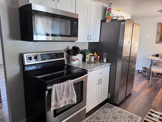 54 W 300 S, Orem, UT 84058 - kitchen featuring appliances with stainless steel finishes, white cabinetry, dark wood-style floors, and light stone counters