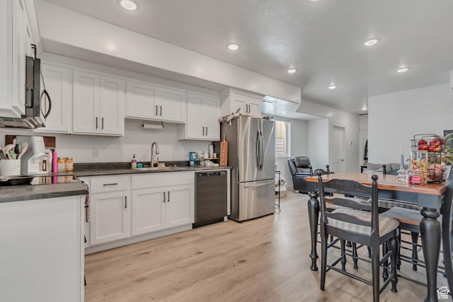 1058 W 570 N, Orem, UT 84057 - kitchen featuring appliances with stainless steel finishes, dark countertops, white cabinetry, light wood-style floors, and recessed lighting
