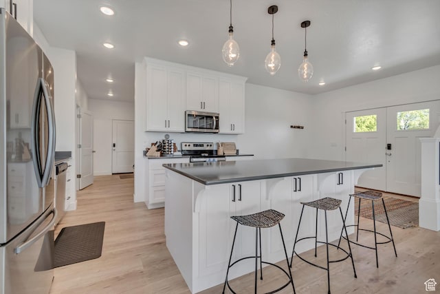 1058 W 570 N, Orem, UT 84057 - kitchen with stainless steel appliances, dark countertops, light wood-type flooring, a breakfast bar area, and a kitchen island