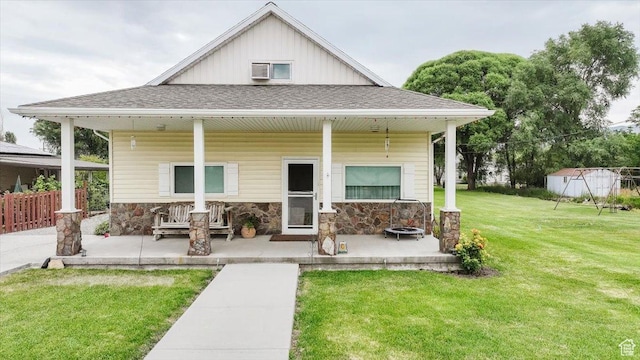 14360 N 6000 W, Garland, UT 84312 - view of front of house featuring covered porch, a front lawn, stone siding, and a shingled roof