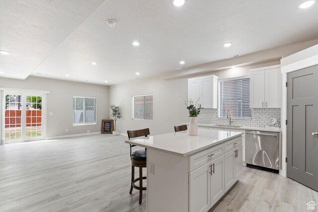 2835 Lincoln Ave, Ogden, UT 84401 - kitchen featuring stainless steel dishwasher, a kitchen bar, light wood finished floors, a center island, and backsplash