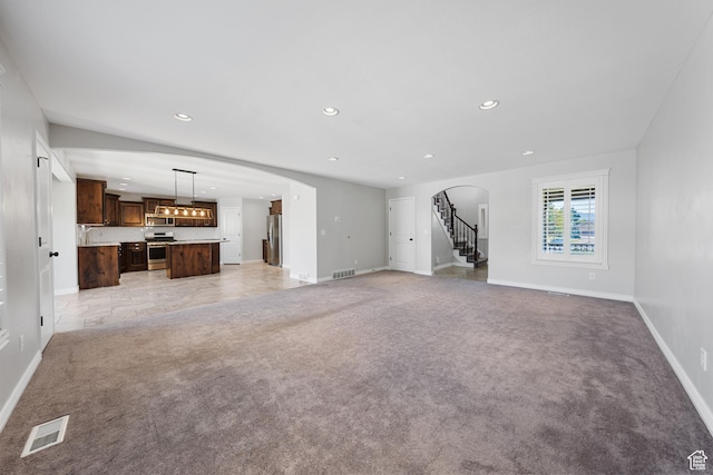 488 N 1375 E, Layton, UT 84040 - unfurnished living room featuring light colored carpet, arched walkways, recessed lighting, and stairs