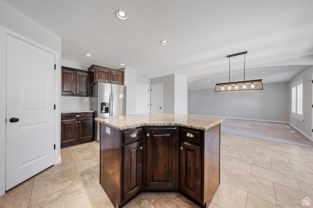488 N 1375 E, Layton, UT 84040 - kitchen featuring stainless steel refrigerator with ice dispenser, tasteful backsplash, dark brown cabinets, light stone counters, and a center island