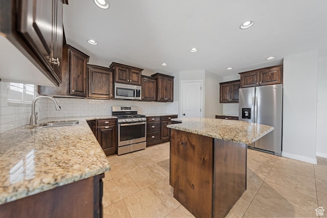 488 N 1375 E, Layton, UT 84040 - kitchen with stainless steel appliances, dark brown cabinetry, a center island, decorative backsplash, and light stone counters