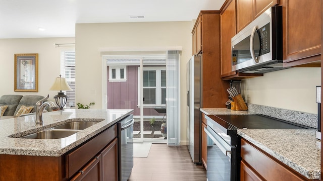 6069 W Franciscotti Dr Unit 473, South Jordan, UT 84009 - kitchen featuring appliances with stainless steel finishes, wood finished floors, light stone counters, brown cabinetry, and recessed lighting