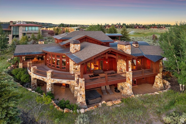 7881 N W Hills Trl, Park City, UT 84098 - back of house at dusk featuring a chimney, stone siding, a patio, and a balcony