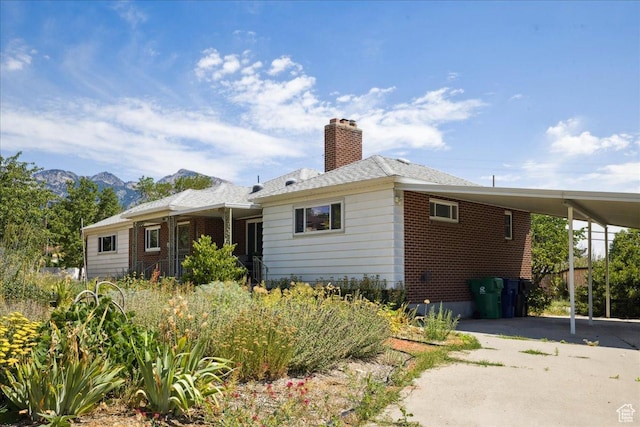 2684 E 2900 S, Millcreek, UT 84109 - rear view of house featuring a carport, driveway, brick siding, a chimney, and a mountain view